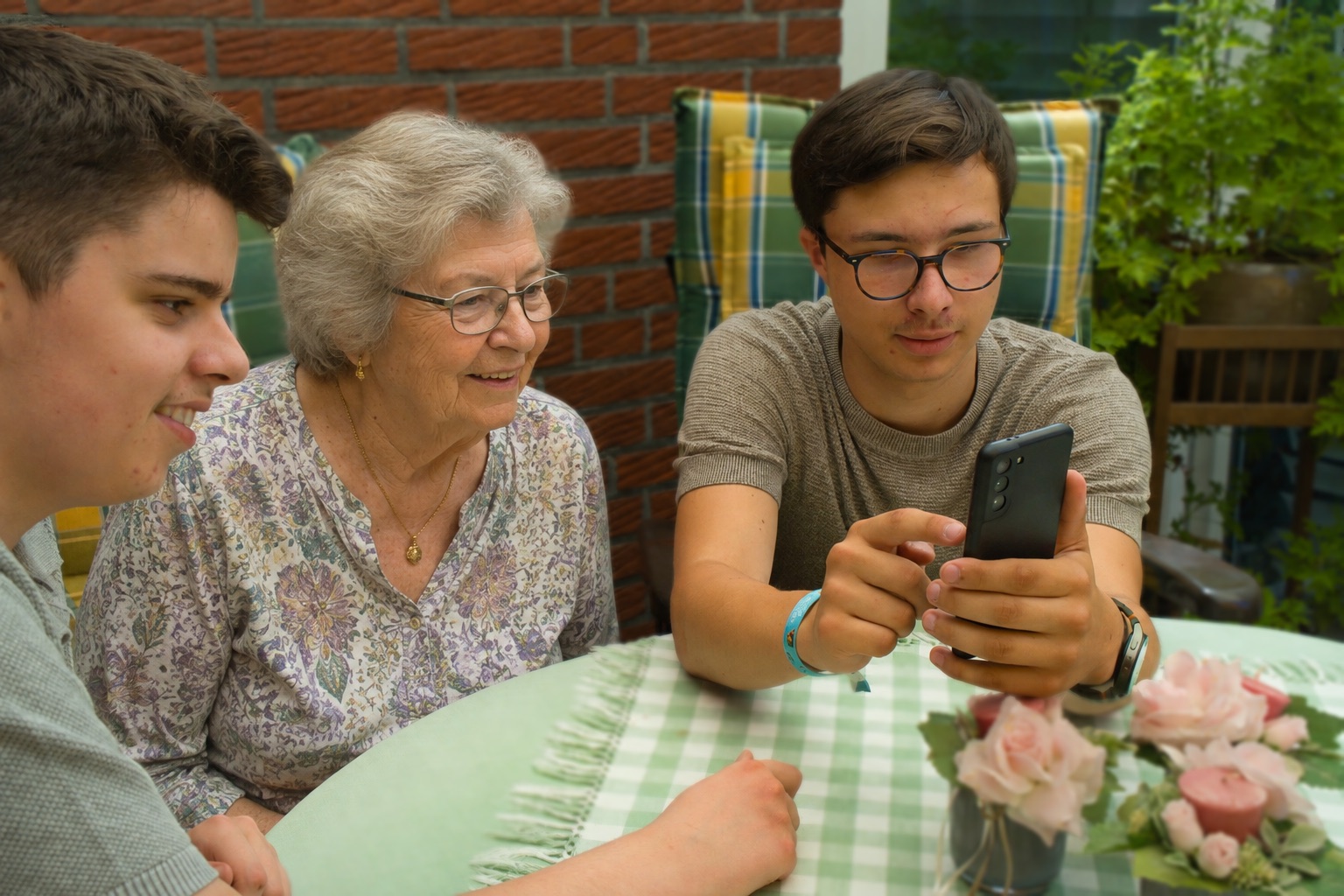 Denis und Jaron erklären einer älteren Dame die ePA am Smartphone